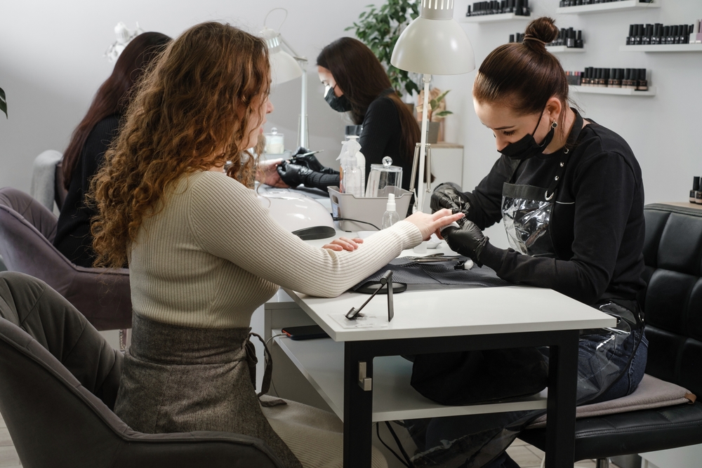 A nail stylist works on a client at a nail salon.